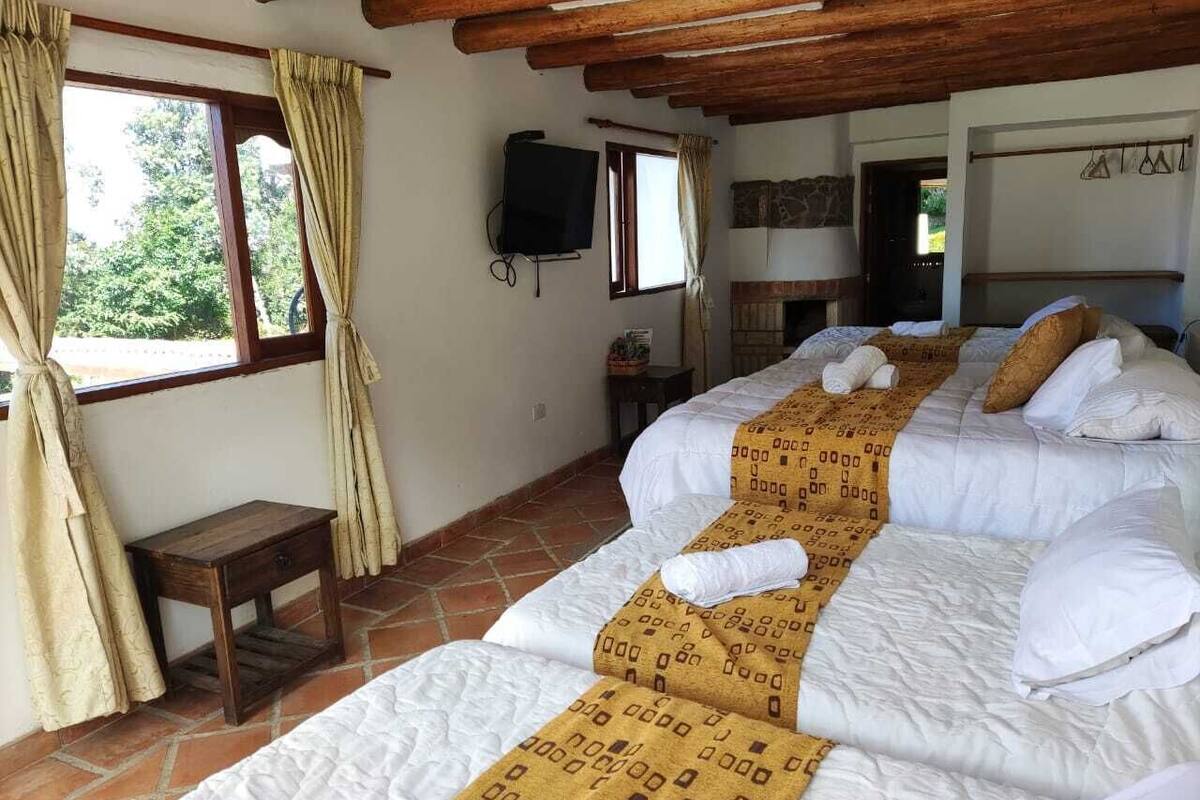 Une chambre avec trois lits, une télévision et une petite table.