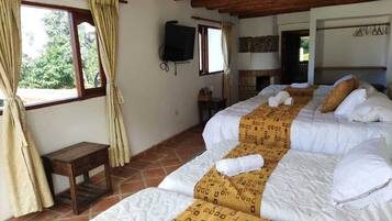 A room with three beds, a television, and a small table.