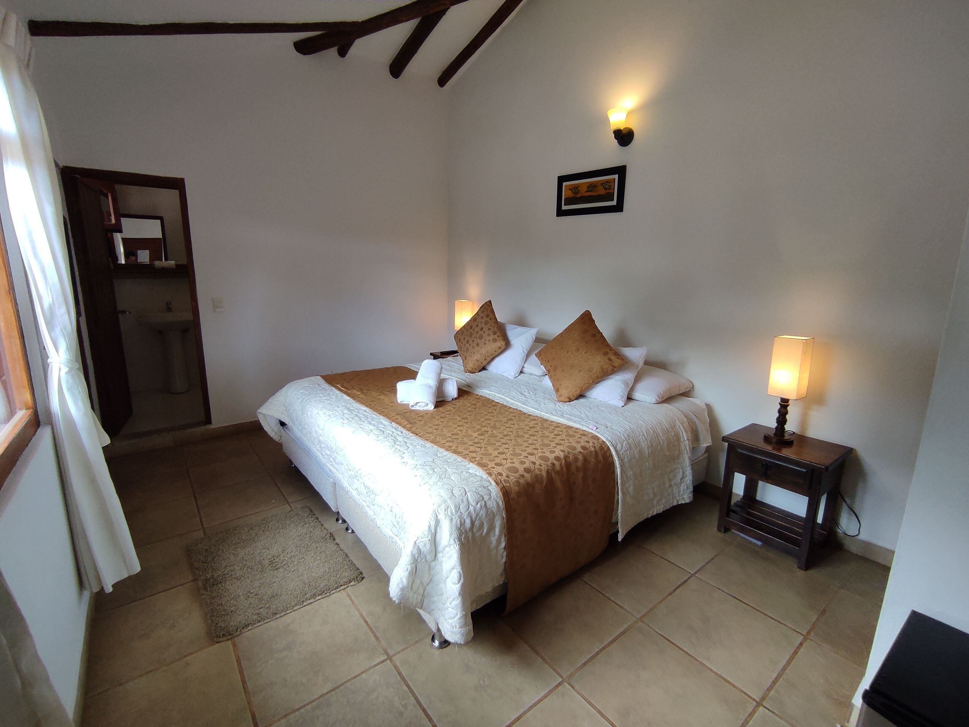 A neatly made bed with a brown blanket and pillows, a bedside lamp, and a small bedside table.