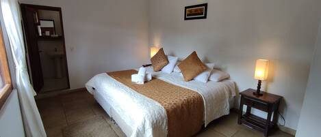 A neatly made bed with a brown blanket and pillows, a bedside lamp, and a small bedside table.