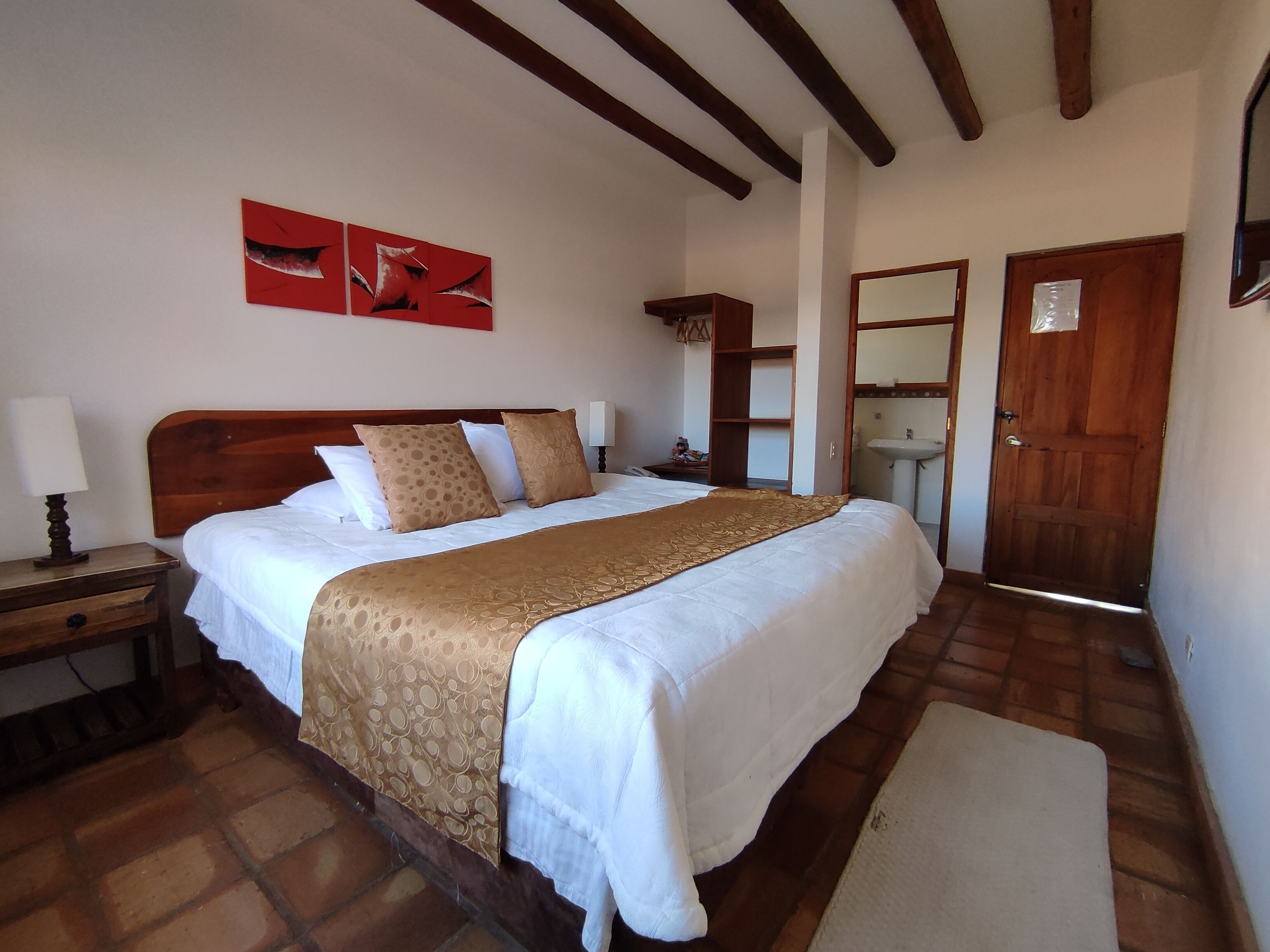 Un dormitorio con una cama de madera, una mesita de noche y un espejo, además de una puerta.