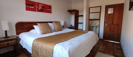 Un dormitorio con una cama de madera, una mesita de noche y un espejo, además de una puerta.