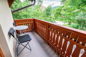 Un balcone con ringhiera in legno, un tavolino e due sedie.