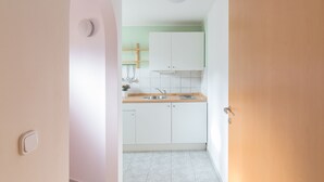 Una cocina estrecha con armarios blancos, una encimera de madera y un lavabo.