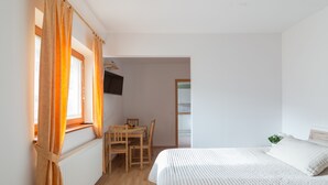Un dormitorio con cama, una mesa de madera, sillas y un radiador.