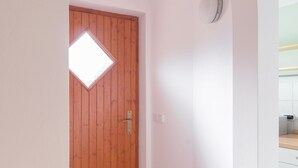 Un pasillo con puerta de madera, una ventana pequeña y suelo de baldosas.