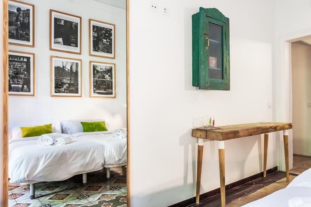 Une chambre à coucher avec un lit, une table de chevet en bois et un mur orné de photographies encadrées.