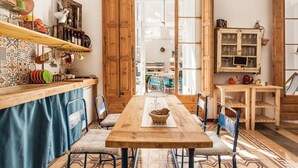 A cozy kitchen with a wooden table, chairs, and a variety of kitchenware on shelves. - Factory Suites Barcelona (Barcelona)
