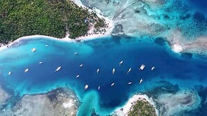 An aerial view of a coastal area with a marina, boats, and surrounding islands. - Cabins in Chichime Island (Narganá)