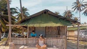A small wooden structure with a corrugated metal roof, situated on a sandy beach with palm trees in the background. - Cabins in Chichime Island (Narganá)