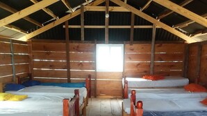 A cabin with two wooden beds, a small table, and a window allowing natural light. - Cabins in Chichime Island (Narganá)
