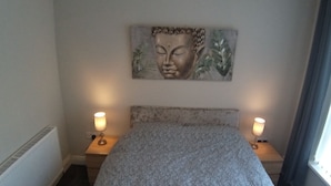 A bedroom with a bed, two bedside lamps, a wall-mounted artwork, and a window with curtains. - Templemore Town House (Belfast)