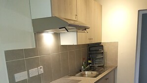 A modern kitchen with wooden cabinets, a stainless steel sink, and a built-in oven. - Templemore Town House (Belfast)