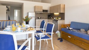 Un espace de vie compact comprenant un coin repas, une kitchenette et un canapé.