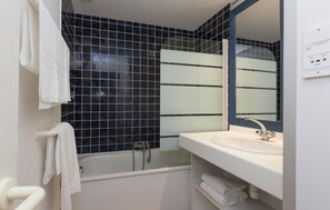 A bathroom with a bathtub, a white sink, and a mirror. - Résidence Odalys Stella di l'Aria (Sartene)