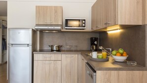 Une cuisine moderne avec des meubles en bois, un four à micro-ondes encastré, un réfrigérateur en acier inoxydable et une machine à café.