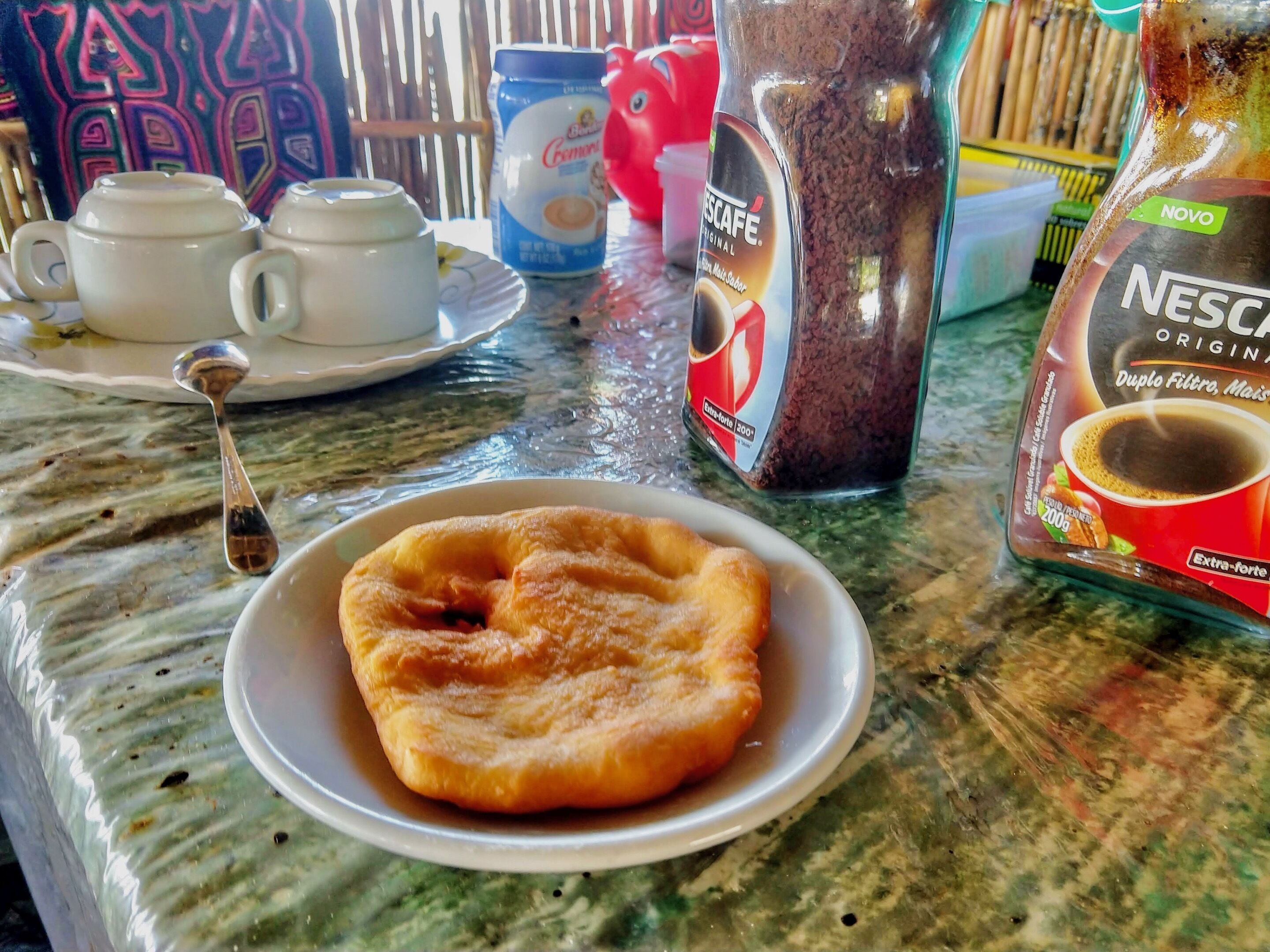 Desayuno con un plato de pasteles, una cafetera y un paquete de Nescafé.
