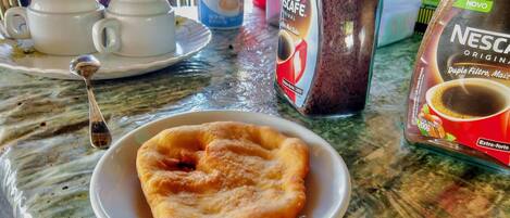 Desayuno con un plato de pasteles, una cafetera y un paquete de Nescafé.
