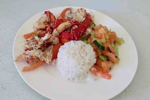 Ein Teller mit weißem Reis, einem Salat und einer Portion gegrilltem Hähnchen.