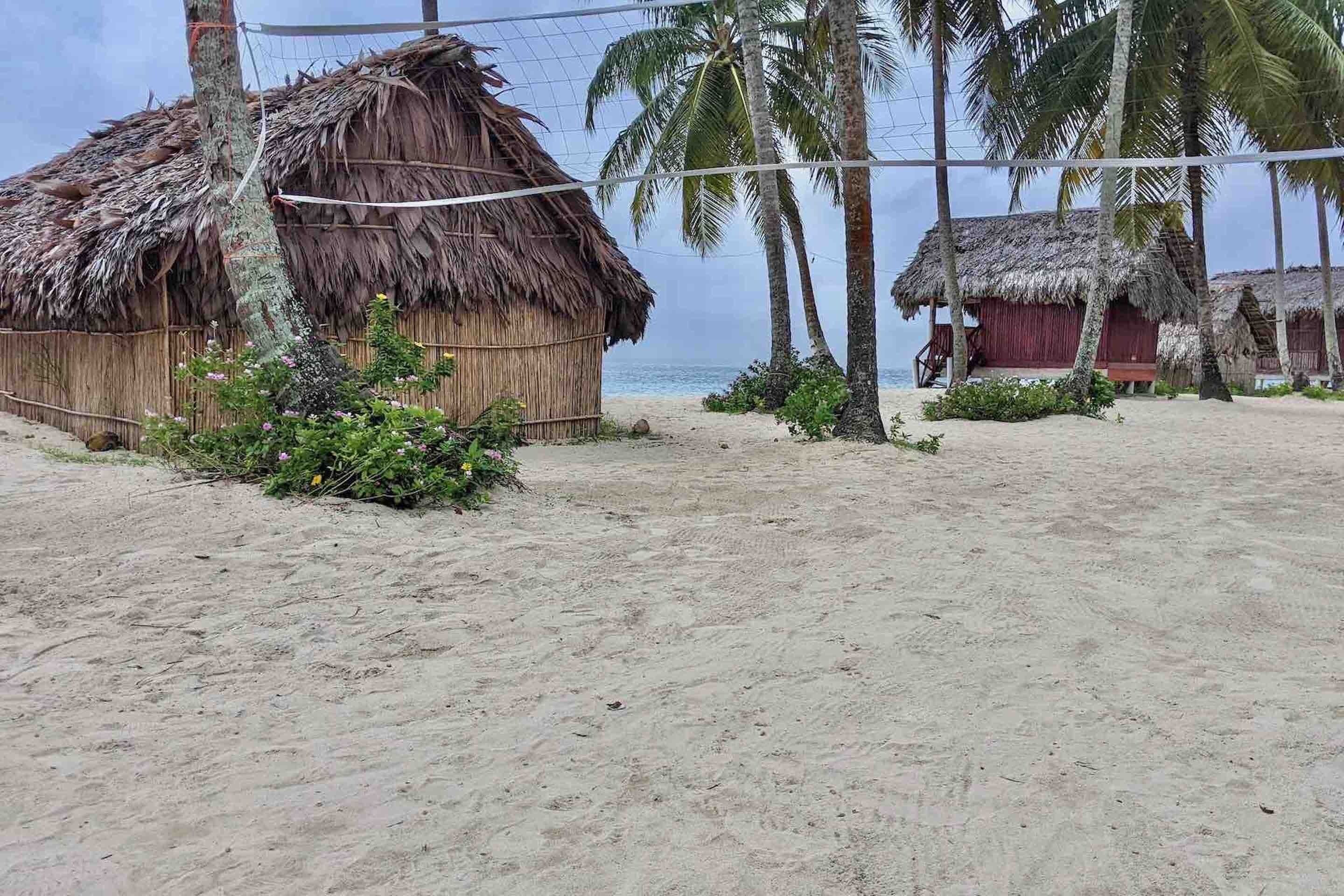 Una playa con cabañas de techo de paja y palmeras.