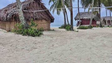 Una playa con cabañas de techo de paja y palmeras.