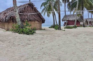 Una playa con cabañas de techo de paja y palmeras.