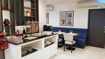 A modern kitchen with a coffee station, seating area, and decorative items on shelves.