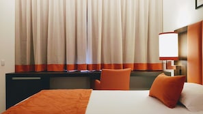 Una habitación de hotel con una cama, un escritorio y una silla.