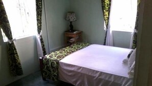 A small, neatly arranged bedroom with a bed, a nightstand, and a patterned rug. - Tapion Beach Suites 1 (Castries)