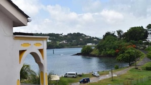 A view of a river with a white building in the foreground, a pathway, and parked cars. - Tapion Beach Suites 1 (Castries)