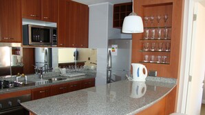 Cozinha moderna com bancadas de granito, eletrodomésticos de aço inoxidável e armários de madeira.