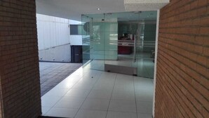 Um hall moderno com paredes de vidro, balcão de recepção e piso ladrilhado.