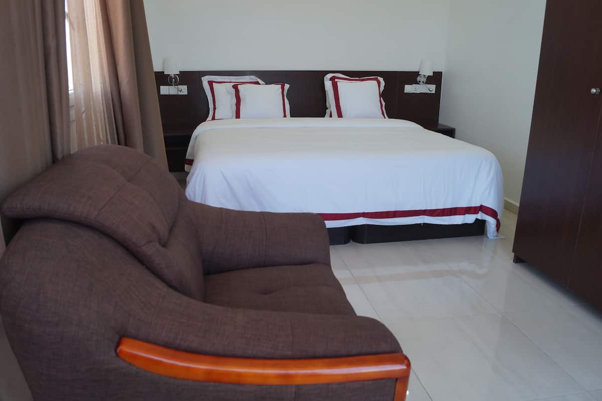 Una habitación de hotel con una cama, un sofá marrón y un armario de madera.
