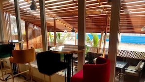 Un restaurante con techo de madera, ventanas amplias y vista al mar.