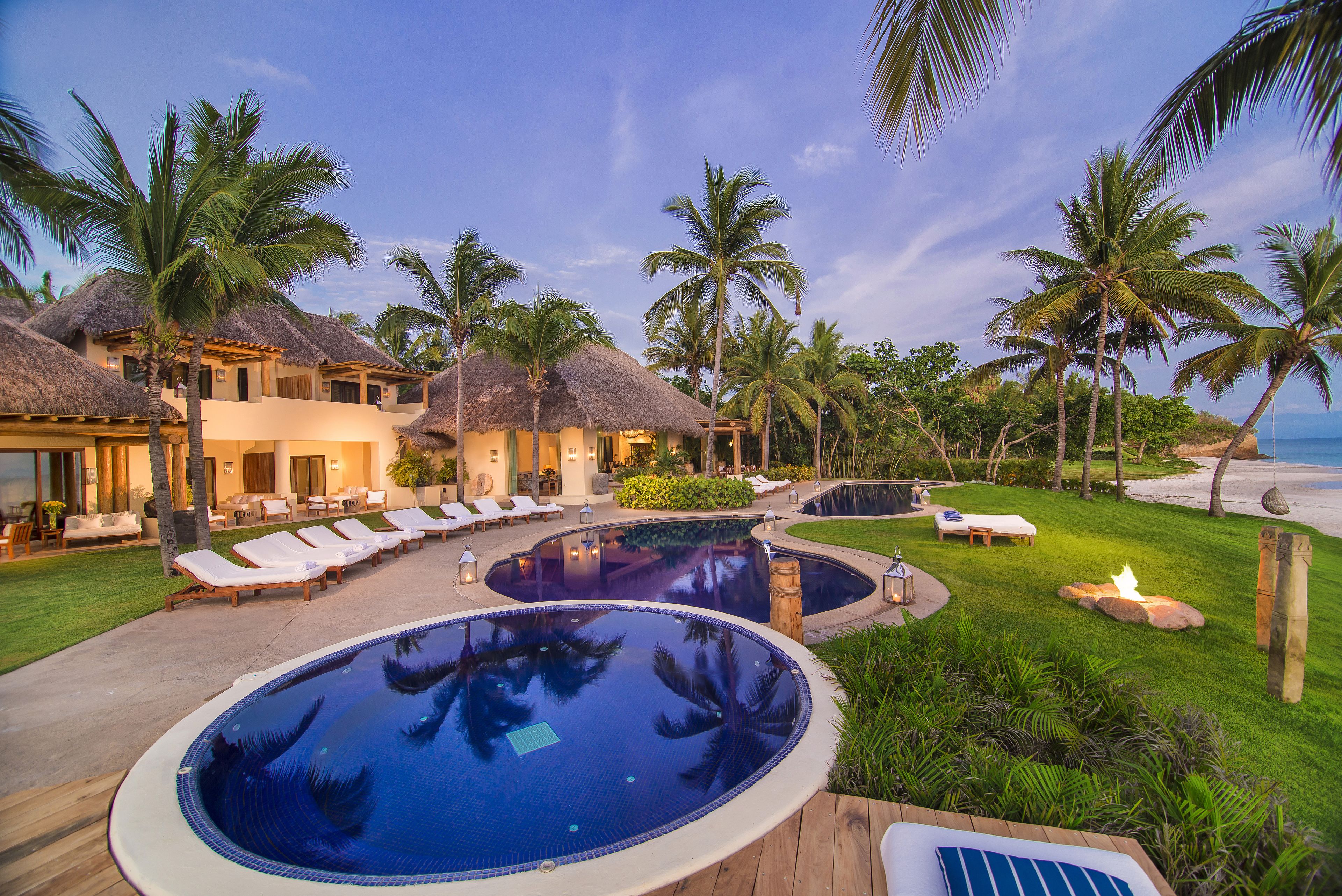 Un resort con piscina, sillas de descanso y palmeras.