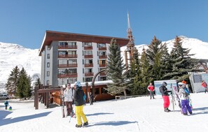 Ein mehrstöckiges Hotel mit einer Seilbahn und schneebedeckten Bergen im Hintergrund.