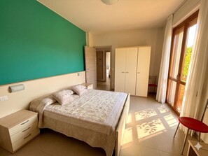 A bedroom with a bed, a nightstand, a dresser, a wardrobe, and a window with curtains. - Appartamento 205 Benaco (Tignale)