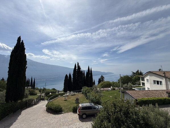A residential area with a paved driveway, a parked car, and a house with a tiled roof. - Appartamento 205 Benaco (Tignale)