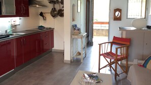 Una cocina con armarios rojos, una zona de comedor con una silla y vistas al exterior.