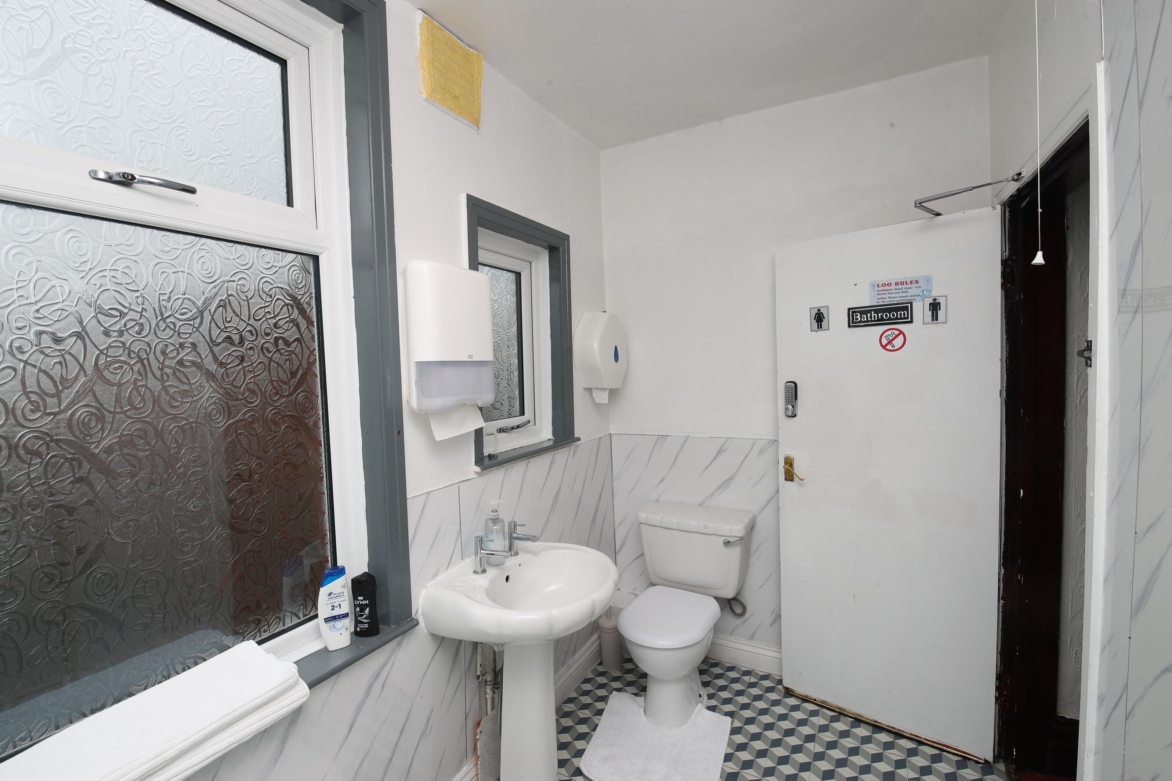 A bathroom with a toilet, sink, and window with frosted glass.