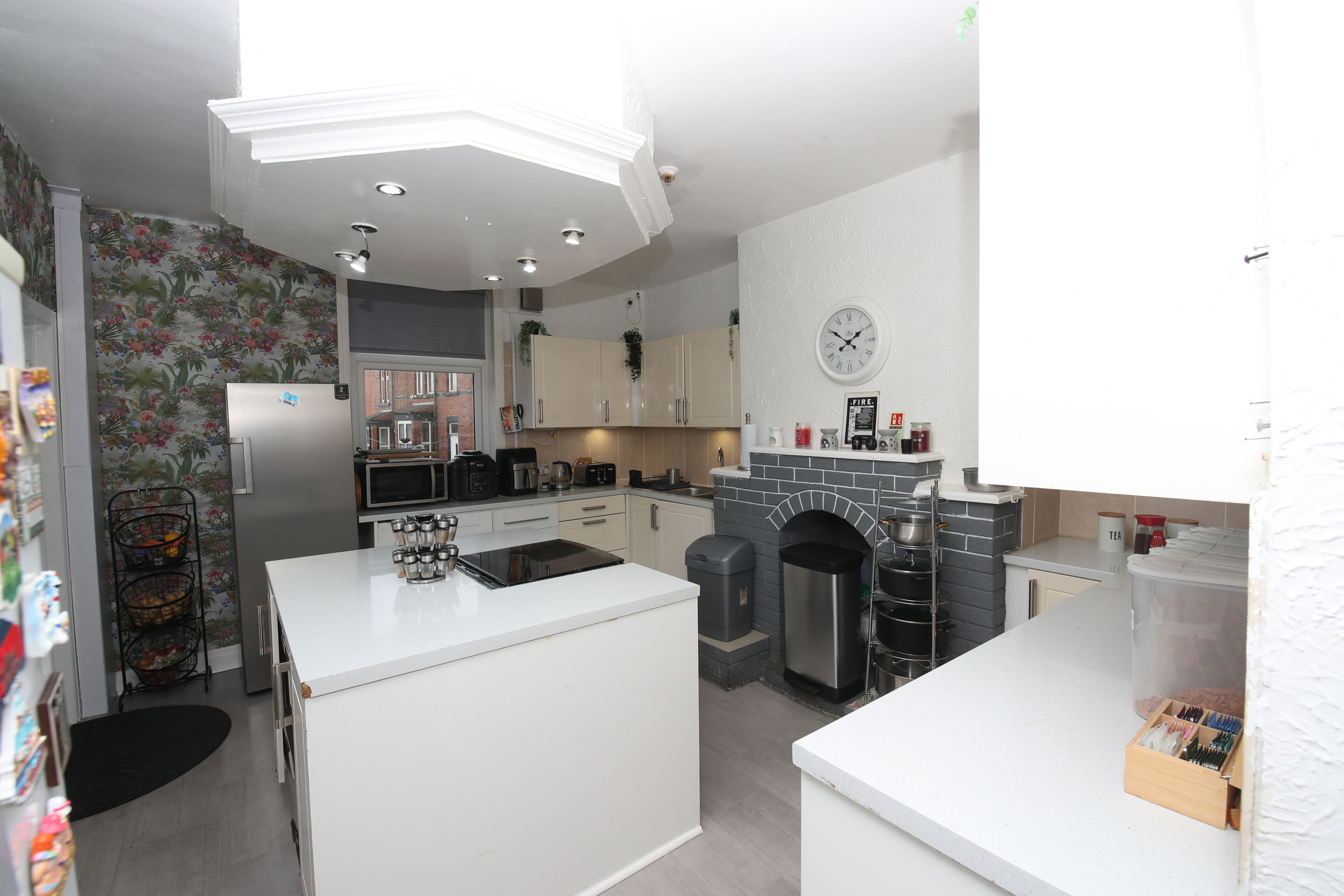 Een moderne keuken met witte kasten, een centraal eiland, een magnetron en een inbouwoven.