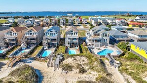 Une zone résidentielle côtière avec des maisons, une plage et une jetée en arrière-plan.