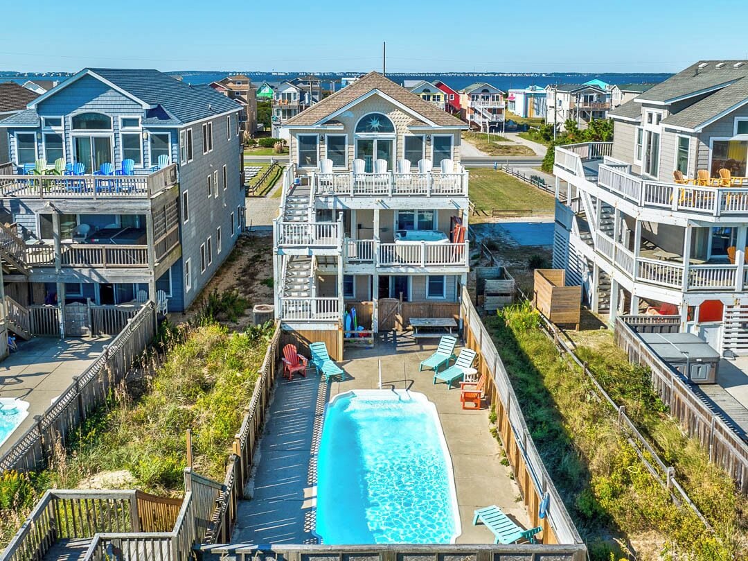 A beachfront residential area with multiple houses, a swimming pool, and a view of the ocean.