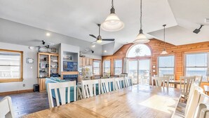 Une cuisine spacieuse avec des meubles en bois, un coin repas doté d’une grande table en bois et un ventilateur de plafond.