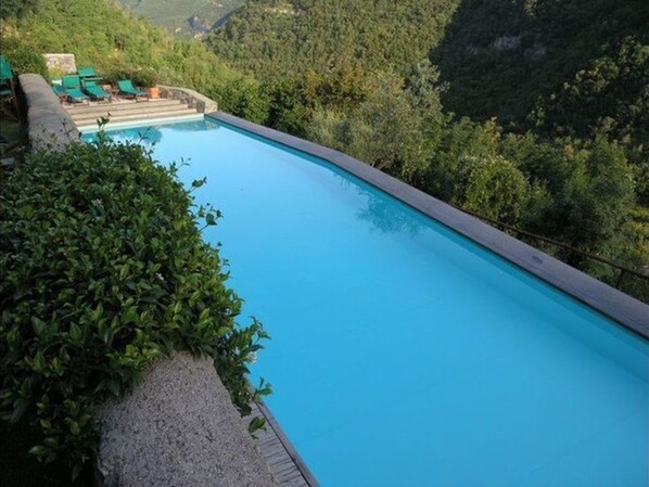 A clear blue pool surrounded by lush greenery, with a few lounge chairs visible in the background. - Cassa di Loggia Sleeps 4 With Pool (Castelbianco)