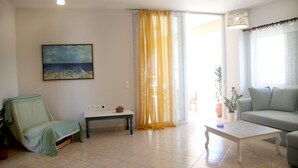 Un salon avec un canapé, une table basse, un banc et un tableau accroché au mur.