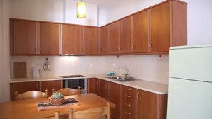 Une cuisine avec des meubles en bois, un plan de travail blanc, un évier, une cuisinière et une table à manger avec des chaises.