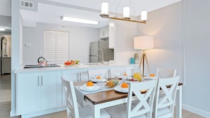 Een moderne keuken met witte kasten, een centraal eiland en een eetgedeelte met witte stoelen.
