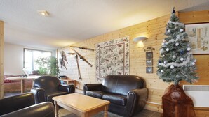 Un salon chaleureux avec un mur en bois, un sapin de Noël et une cheminée.