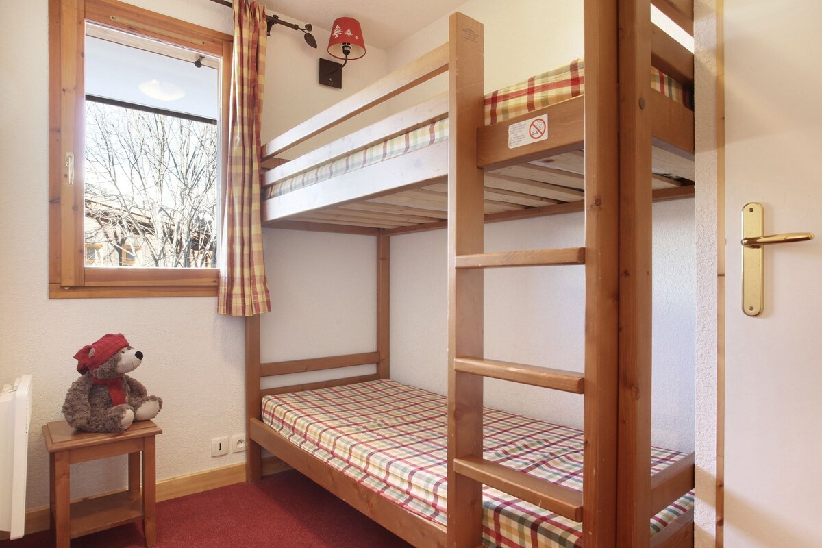 A bunk bed room with a window, a teddy bear, and a lamp.